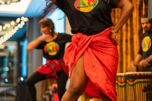 Dancers in black t-shirts and red skirts perform a coordinated routine on stage.