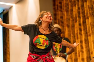 Dancers perform joyfully in a warmly lit performance space with colorful decorative elements.