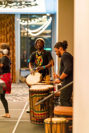 Musicians play traditional African drums during an indoor performance.