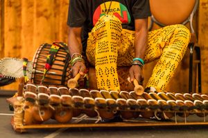 Close-up of traditional wooden percussion instrument with colorful African textile patterns.
