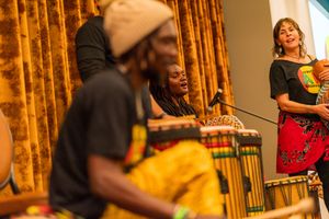Musicians playing African drums and performing traditional music against golden curtain background.