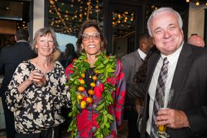 Formal evening reception with guests mingling and socializing around floral decorations.