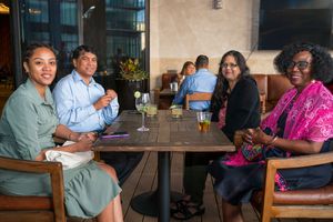 Groups of people enjoy casual dining and conversation at restaurant tables.