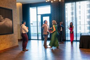 A row of people standing near large windows in a modern interior space.