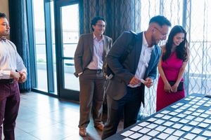 Bright sunlit venue space with guests gathering near large windows.