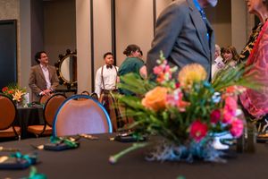 Professional event space with floral centerpieces and presentation screen setup.