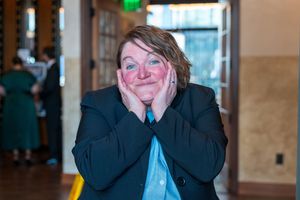 Person in business attire making an excited expression with hands on cheeks.
