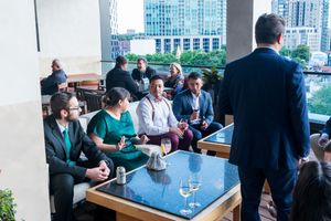 Business professionals gathered for drinks and networking on an urban rooftop terrace.