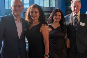 Four attendees pose together for a photo at an evening business function.