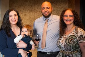A group of adults and an infant gather together for a casual indoor portrait.