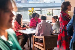 People gathered around tables at a casual meeting or social event in a bright space.