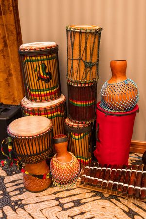 Collection of traditional African drums and percussion instruments displayed against a brown curtain.