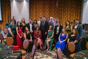 Large group photo of event attendees in formal attire seated in rows.