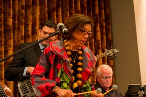 Musician in festive red jacket performs with guitar during evening entertainment.
