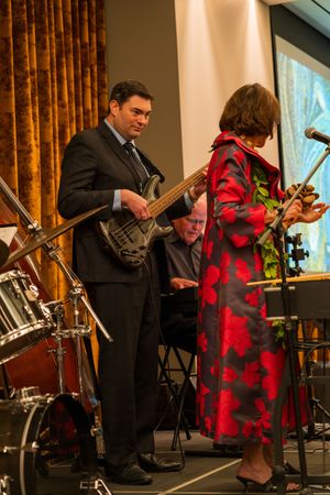 Jazz band performs on stage with bassist in suit and musician in flowing red dress.