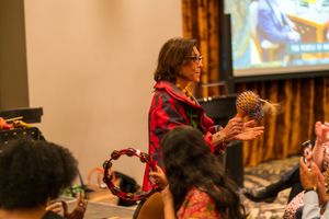 Several people gathered in an indoor venue engaging in interpretive dance movements during a group activity.