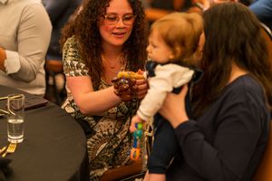 Guests engaging in conversation during formal dinner event at round table.