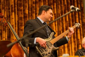 Bass guitarist playing during a live musical performance with warm stage lighting.