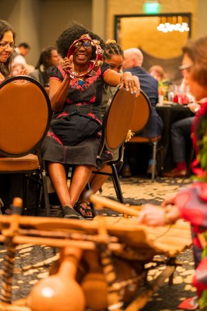 A person in festive attire enjoys a lively moment while seated at a formal dining event.