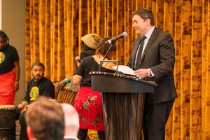A presenter speaks at a podium during an elegant banquet event.