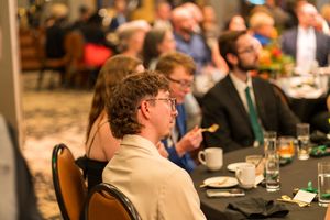 People seated at formal tables during a business or conference event.