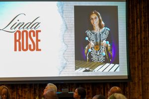 Presentation slide showing 'Linda Rose' with projected image on screen in an auditorium.