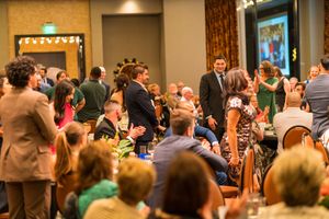Large audience gathered in formal attire at an elegant indoor event venue.