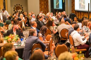 Large banquet hall filled with attendees seated at round tables for an elegant evening event.