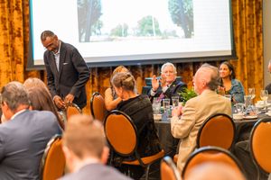 Corporate event audience watching presentation in elegant venue with gold drapes.