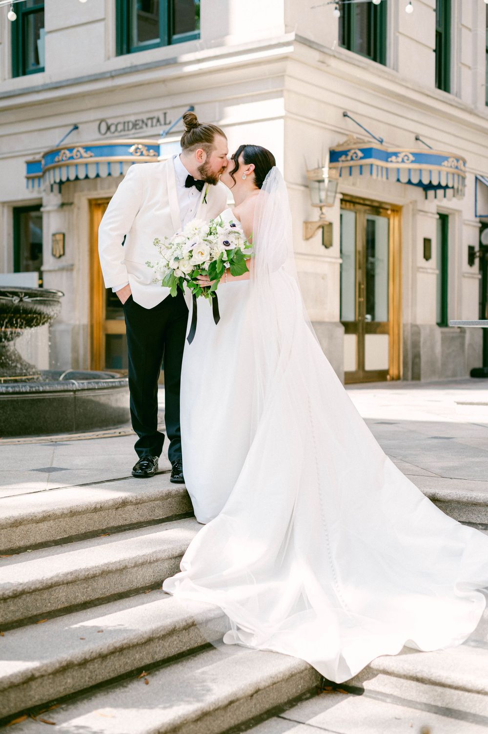 Elegant wedding photos on grand stone steps of historic building with classical architecture.
