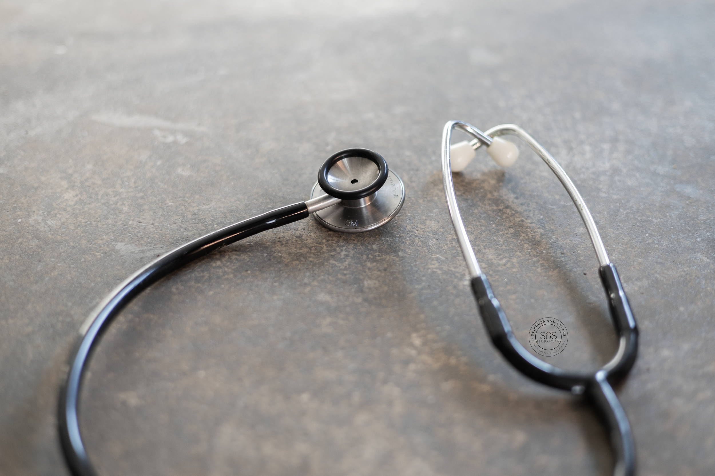 Medical stethoscope lying on gray textured surface.