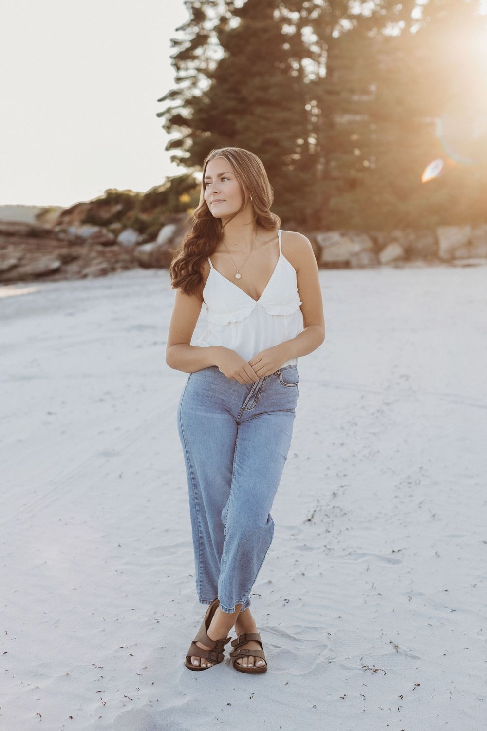 Senior girl laughing while walking along the shoreline during golden hour beach photo session in Maine.