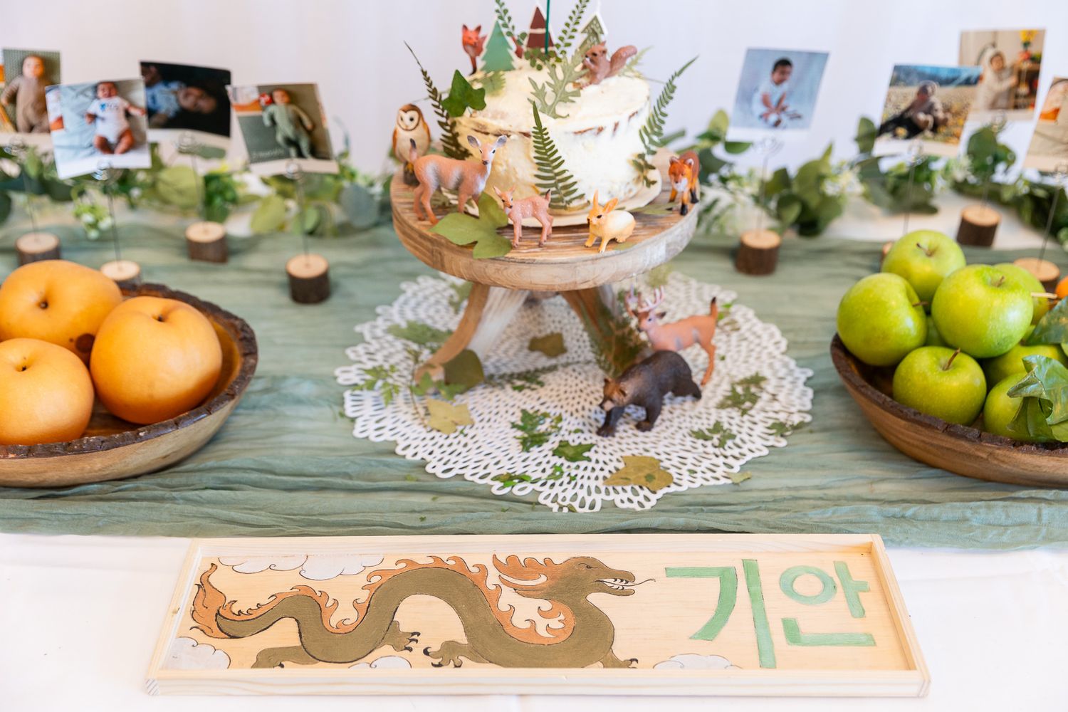 Decorative gold tea set on lace doily with green and orange fruits arranged on mint green table.