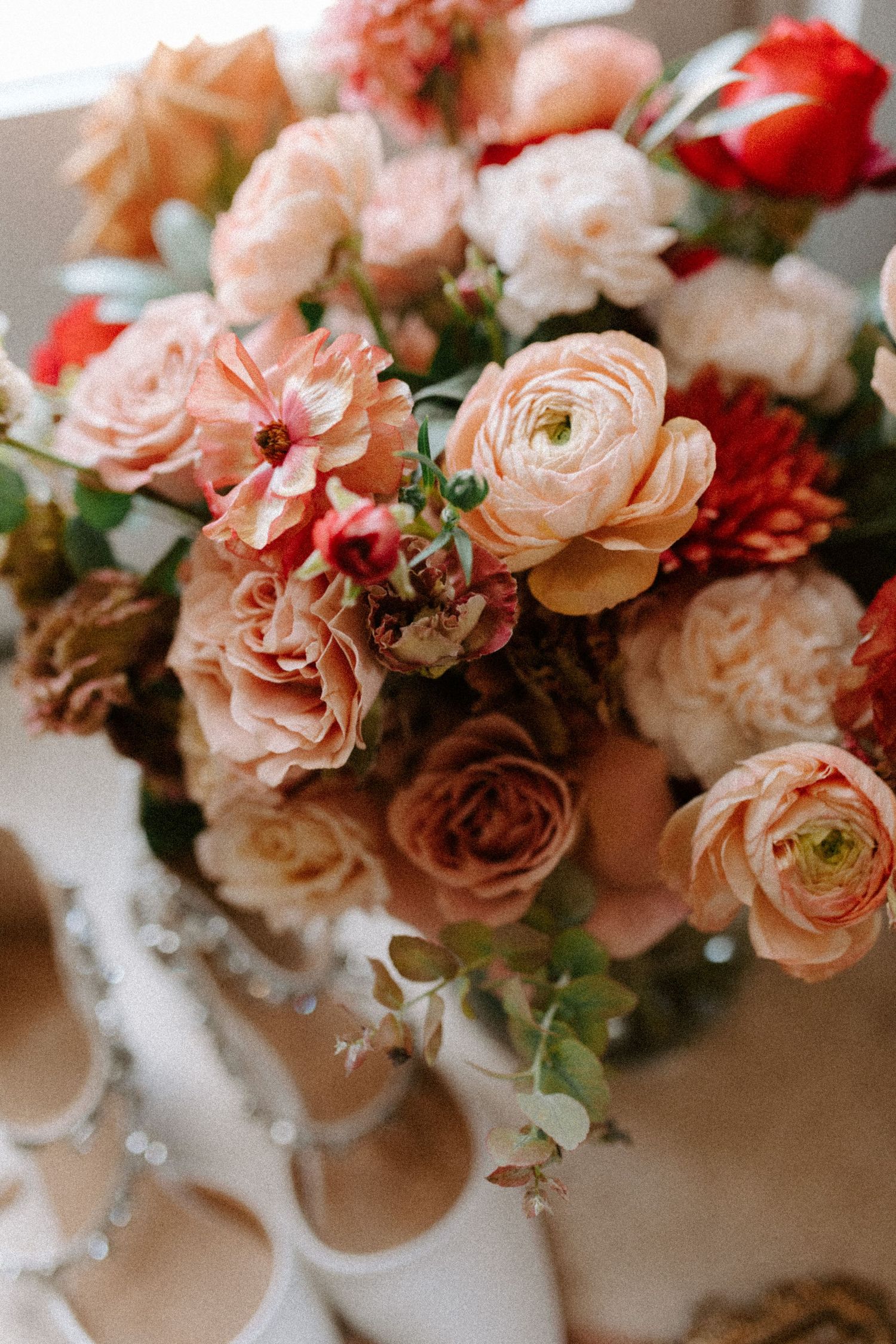 Romantic bouquet of blush pink and coral roses with red accents in soft focus.