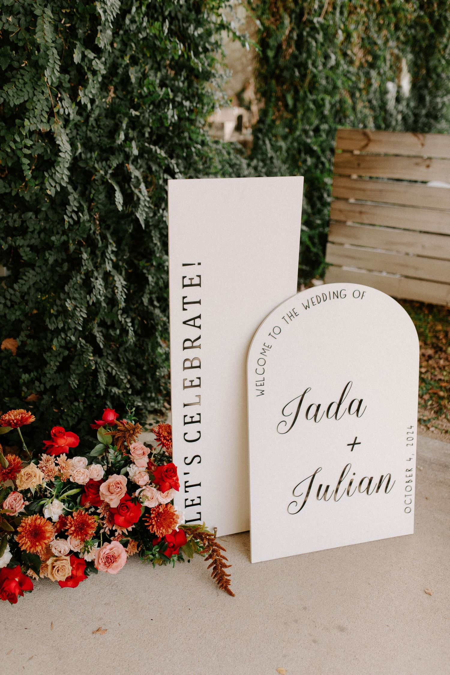Wedding signage for Jada and Julian displayed with pink and red floral arrangements.