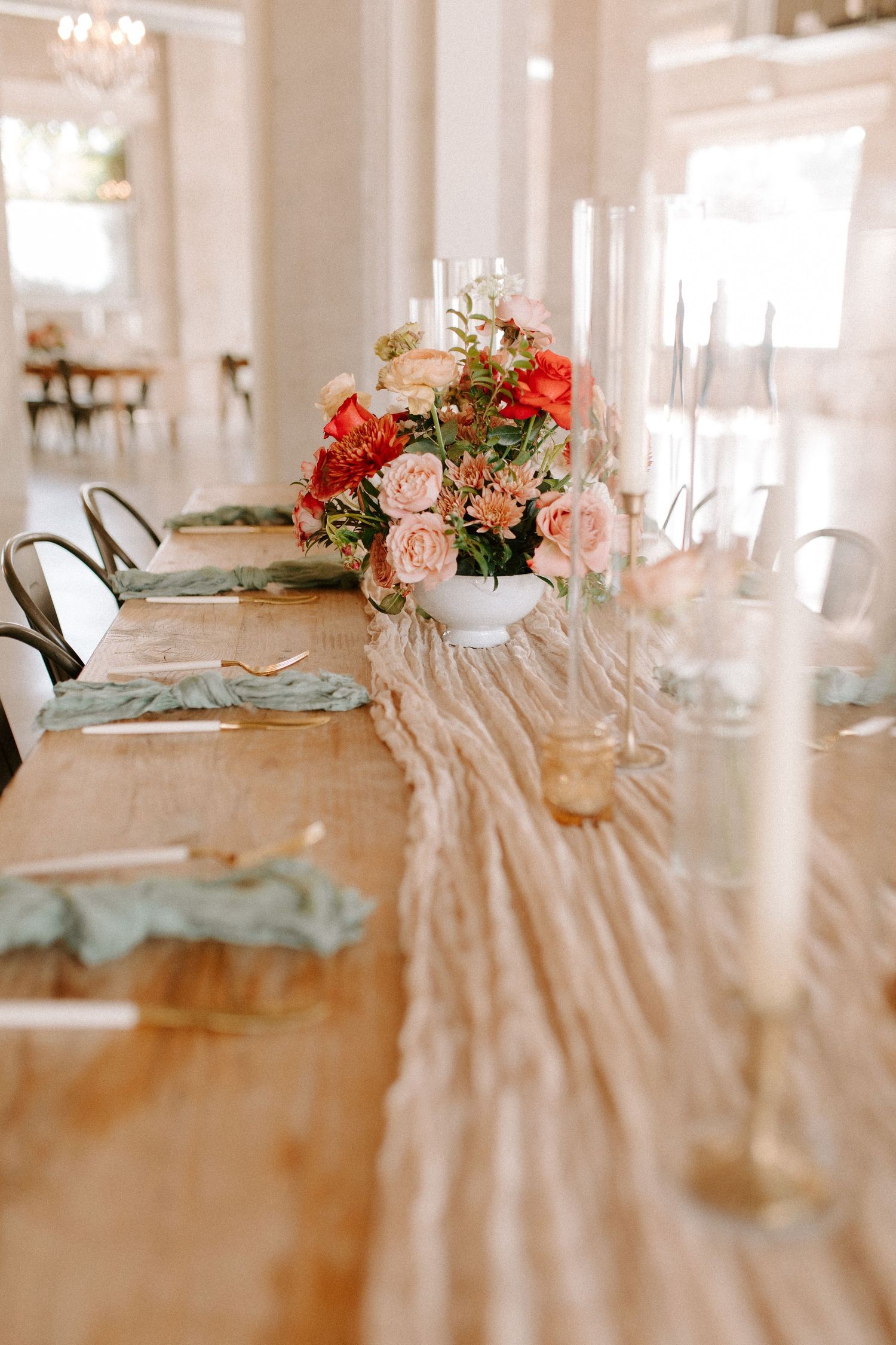 Elegant wedding reception table with floral centerpieces and gauzy table runner.