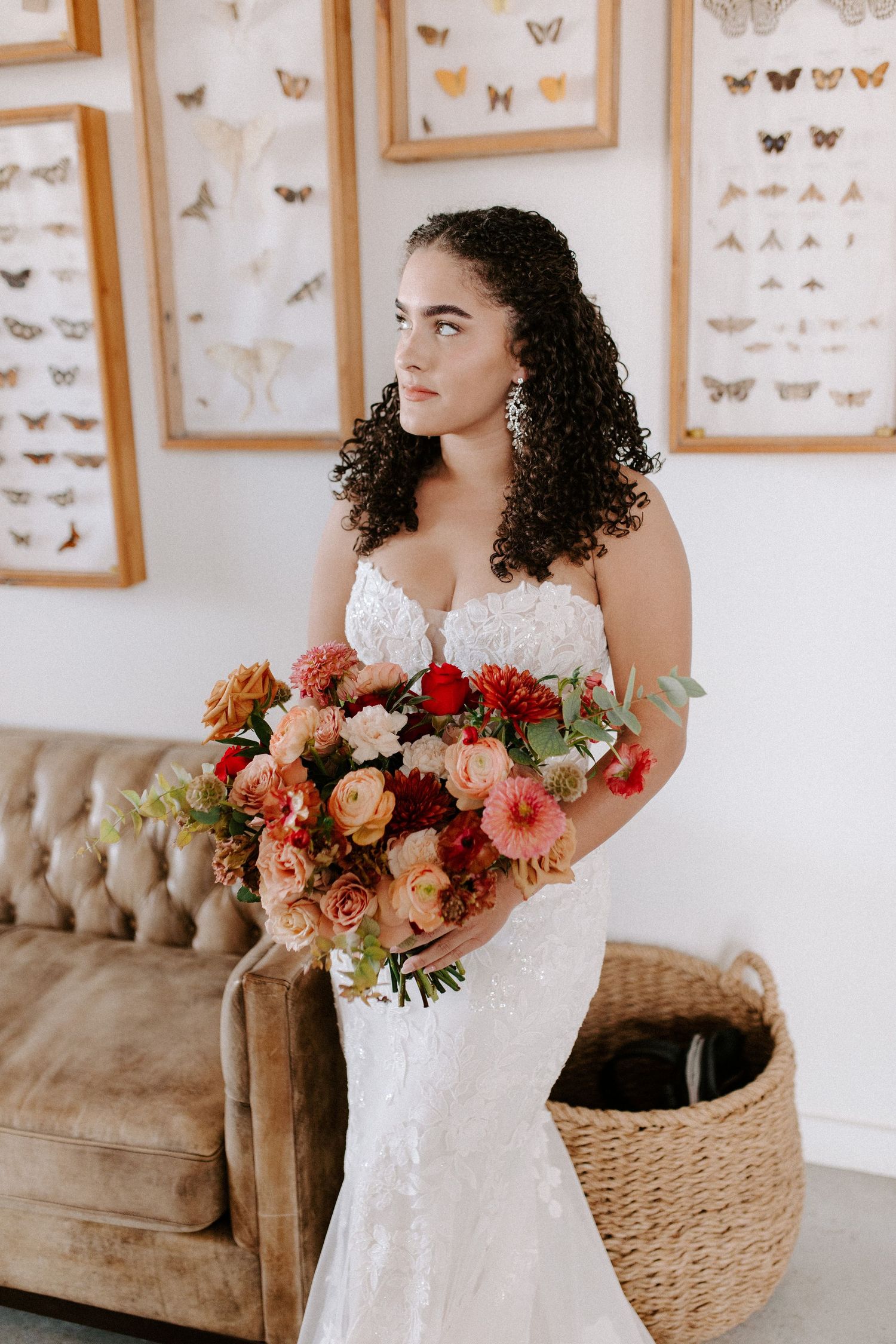 Elegant bridal portrait featuring a vibrant bouquet against a wall of butterfly artwork.
