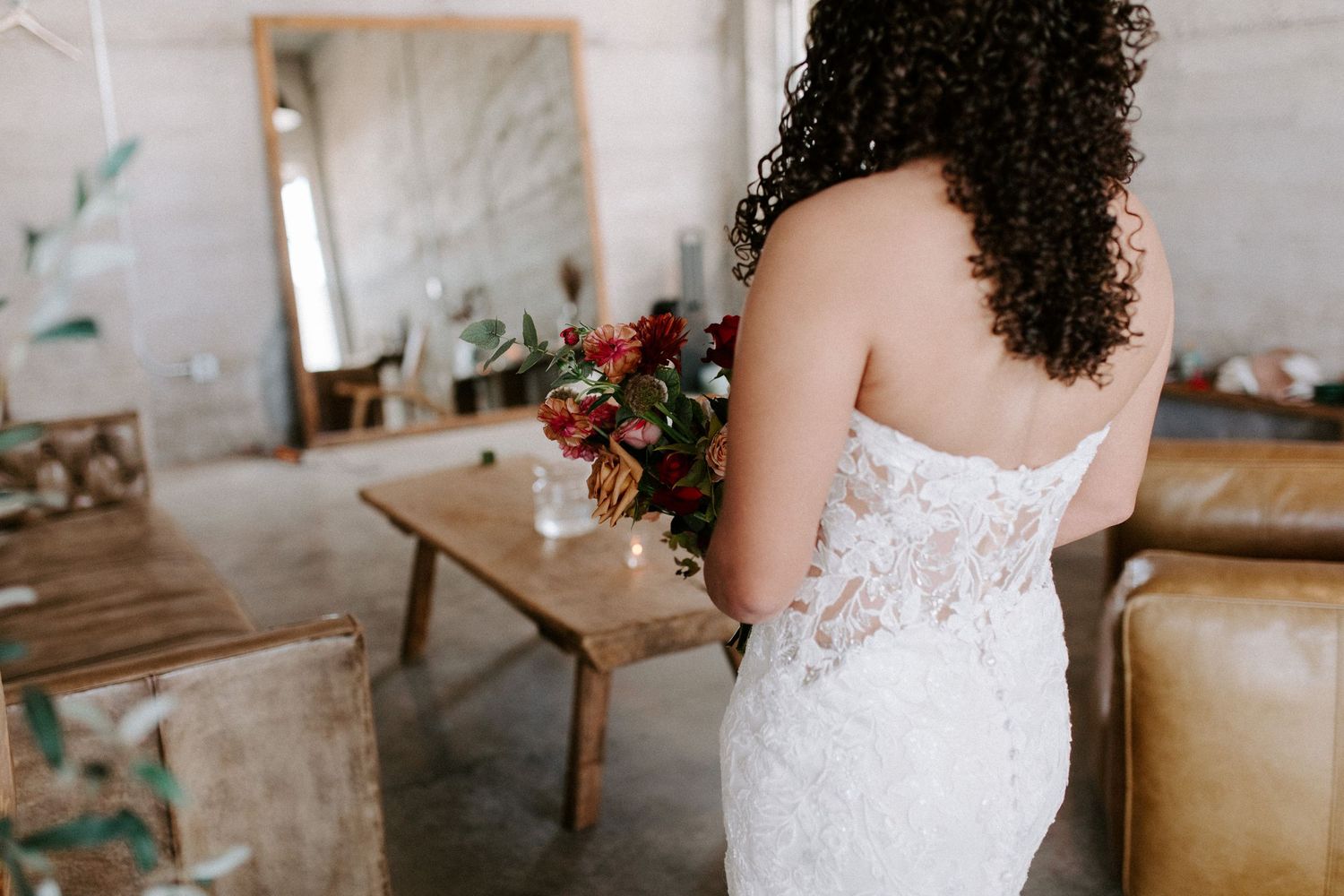 Back view of a detailed lace wedding dress with floral bouquet.
