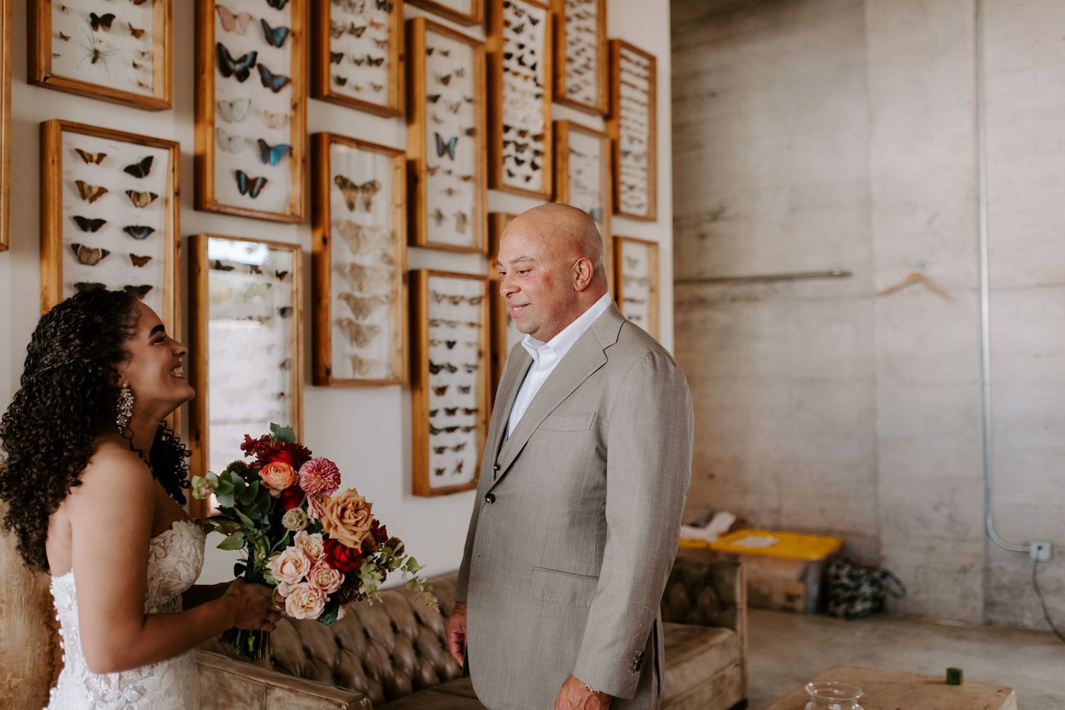 A wedding moment captured in front of vintage butterfly artwork displays.