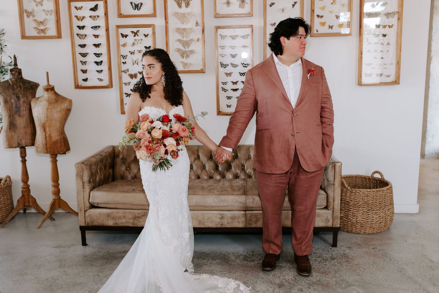 A wedding portrait in a room decorated with butterfly specimens and vintage furniture.