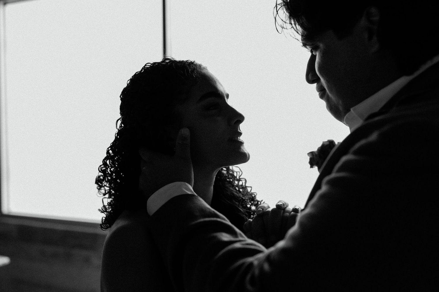 Intimate black and white silhouette of couple in romantic embrace during wedding dance.