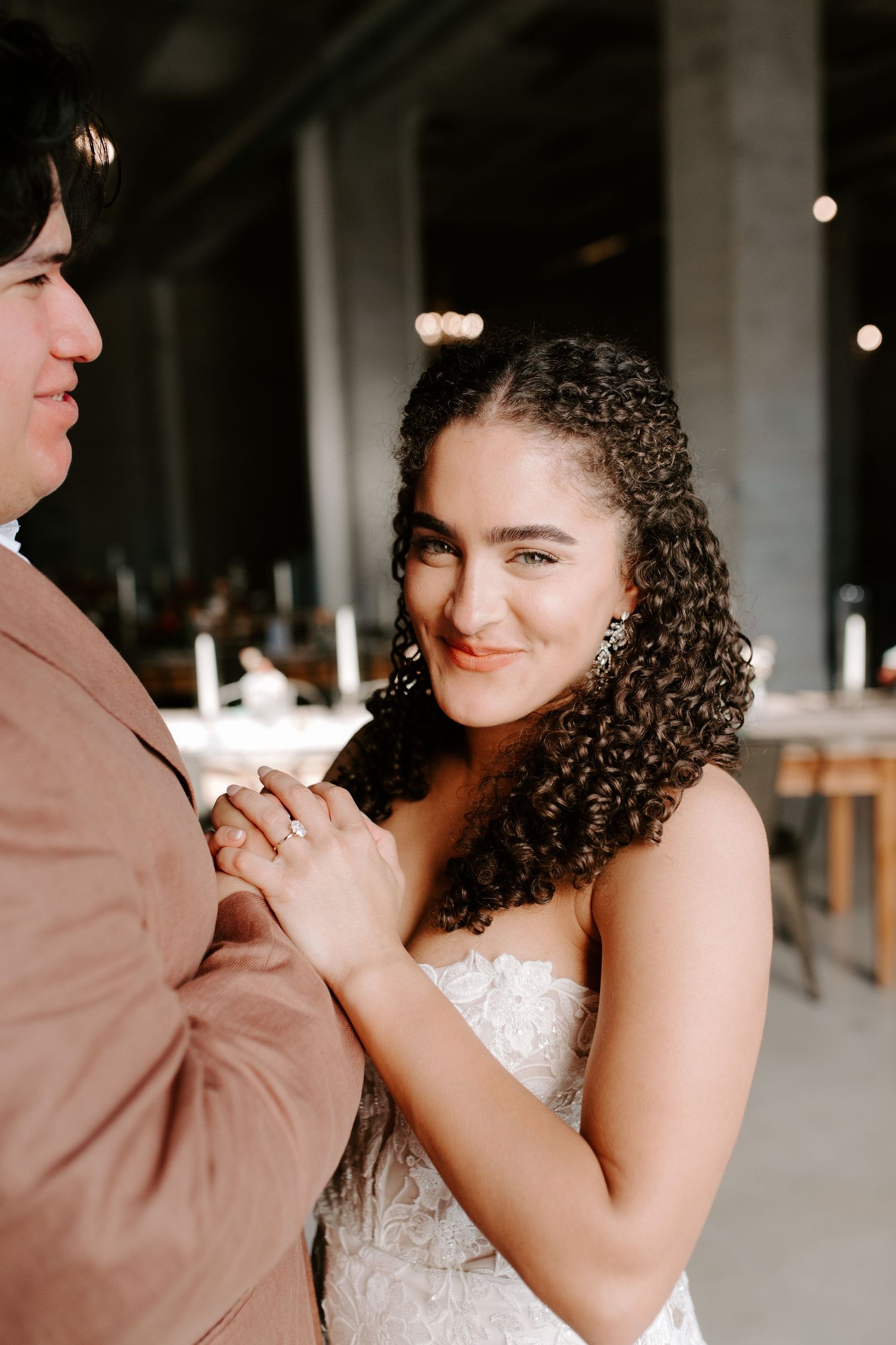 Couple shares tender moment during first dance in elegant venue with industrial details.