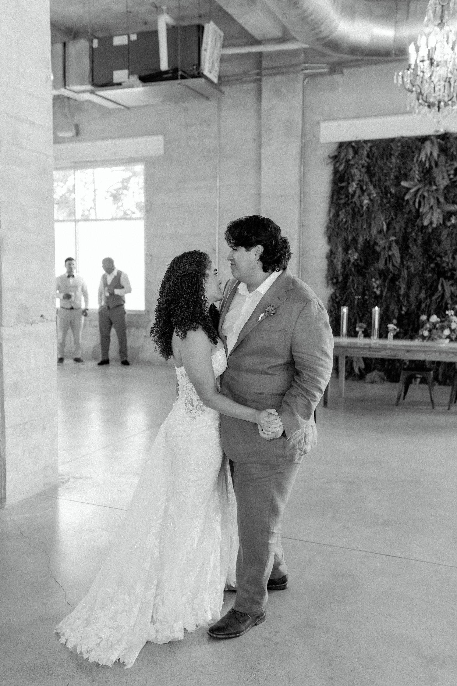 Black and white capture of couple's first dance in industrial-style wedding venue.