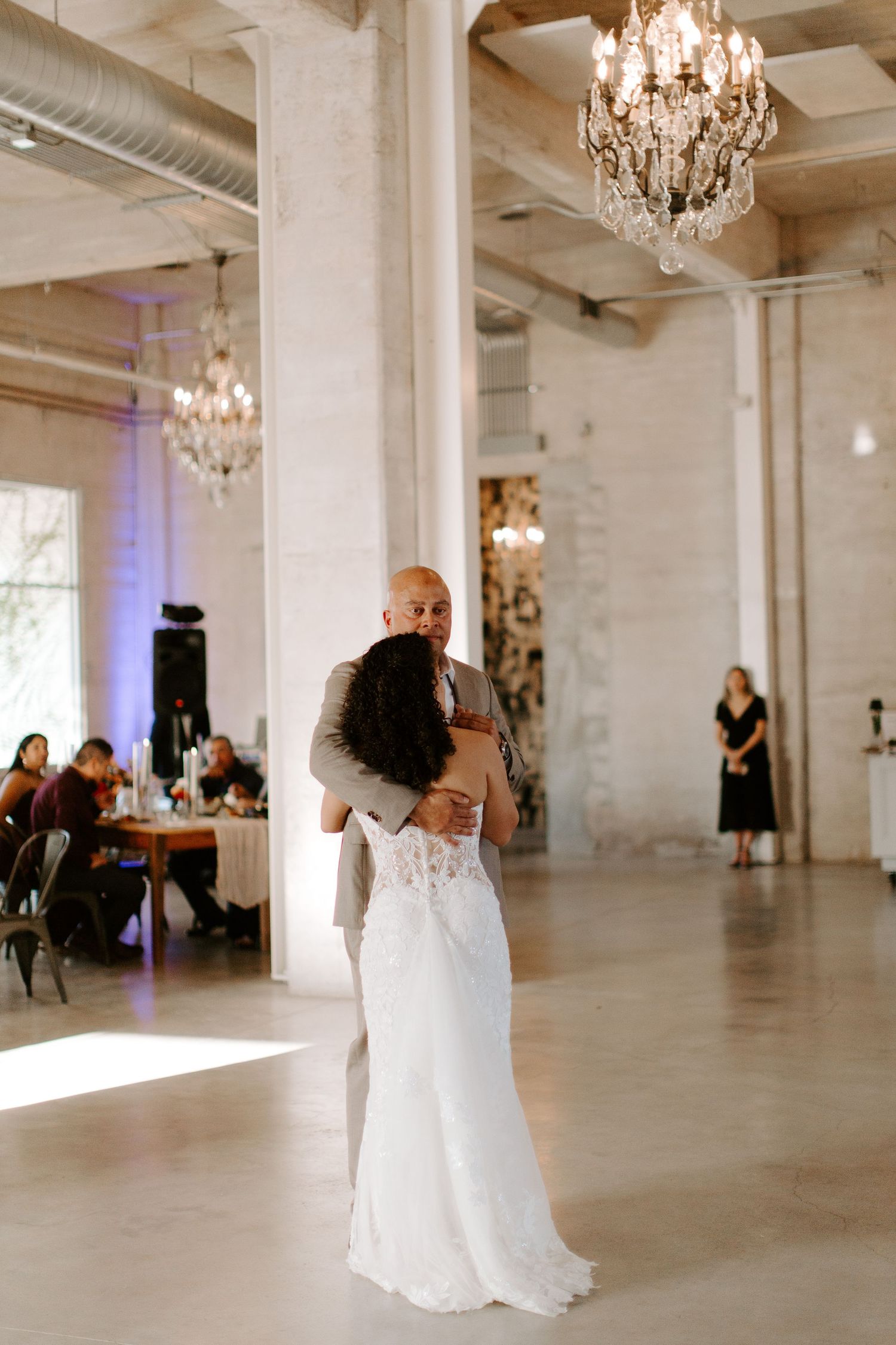 A couple shares their first dance at a wedding reception in an elegant venue with crystal chandeliers.