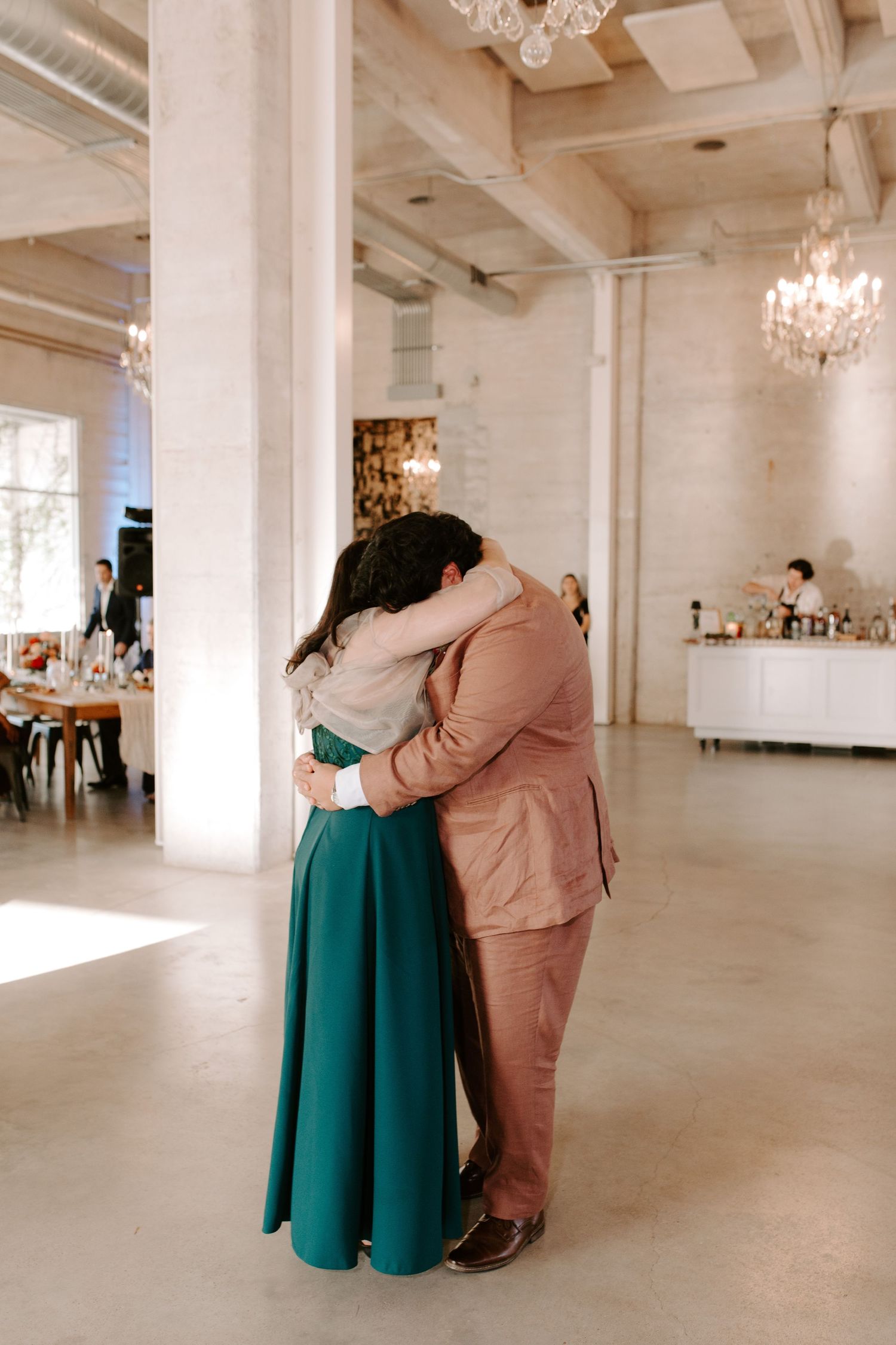 A romantic moment between two people dancing in formal attire at an elegant venue.