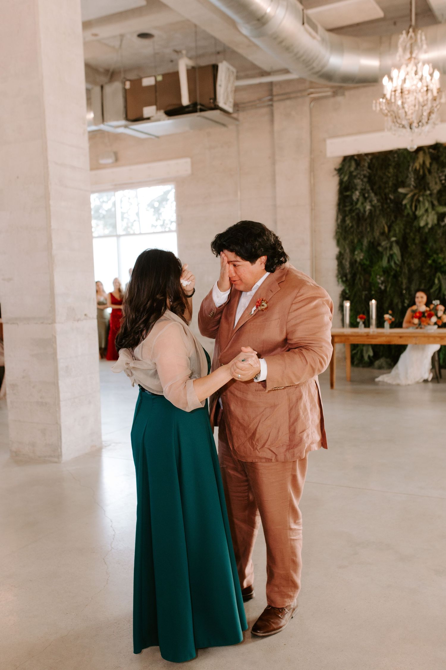 An emotional dance between two people, one in a teal dress and another in a tan suit.