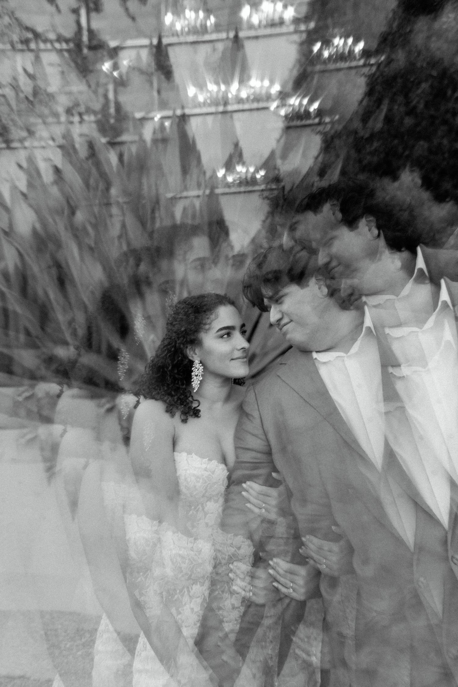 Artistic black and white multiple exposure wedding portrait with chandeliers in background.
