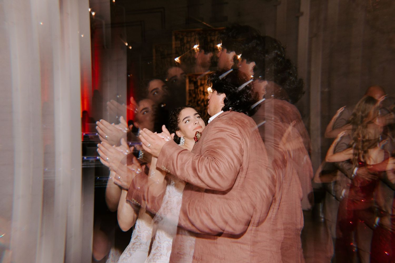 Dancing couple at wedding reception with motion blur effect in salmon and white attire.