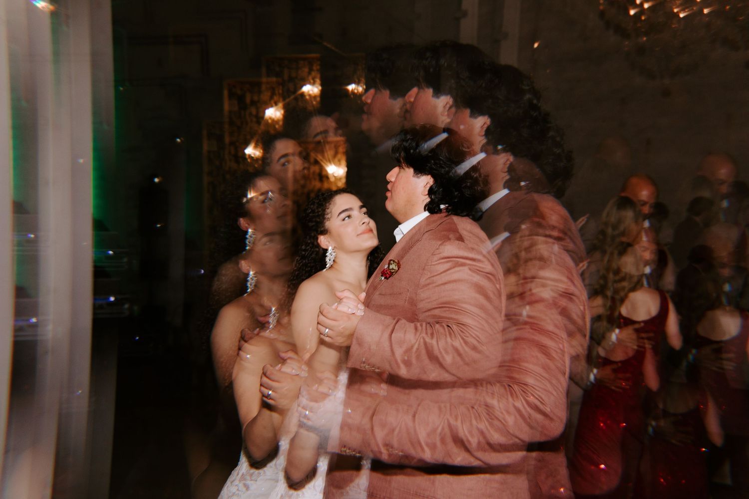 Joyful couple dancing and laughing at wedding reception with motion blur.
