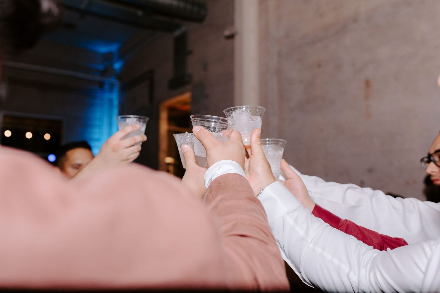 Wedding guests raise glasses in a celebratory toast at a reception venue.